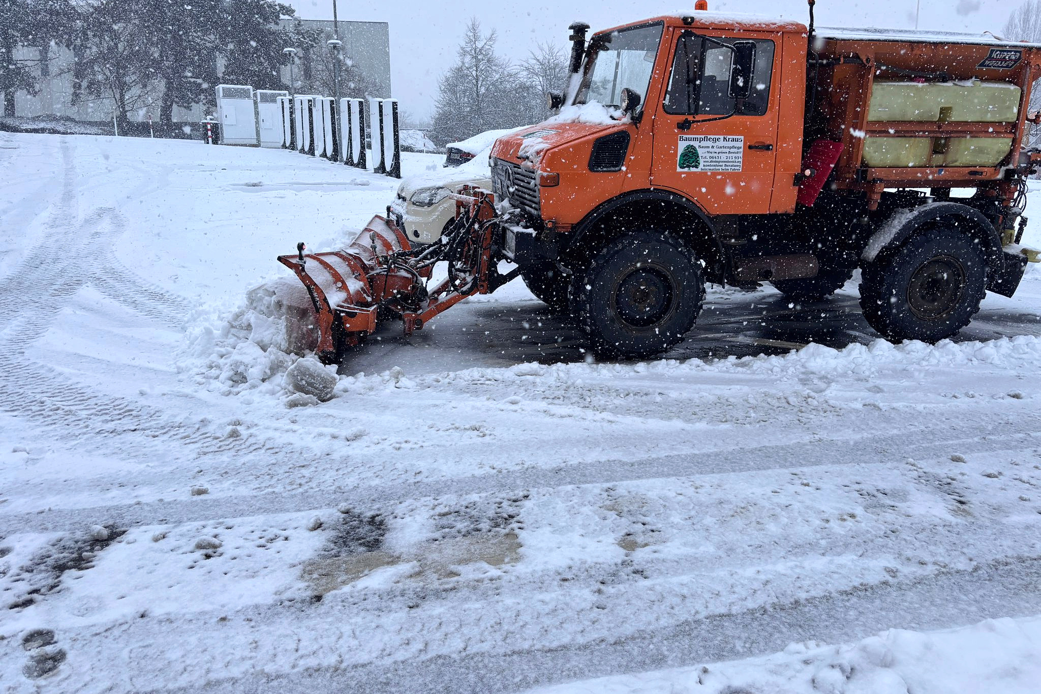 Unimog mit Schneepflug bei der Räumung einer verschneiten Gewerbe- und Parkplatzfläche in Limburg