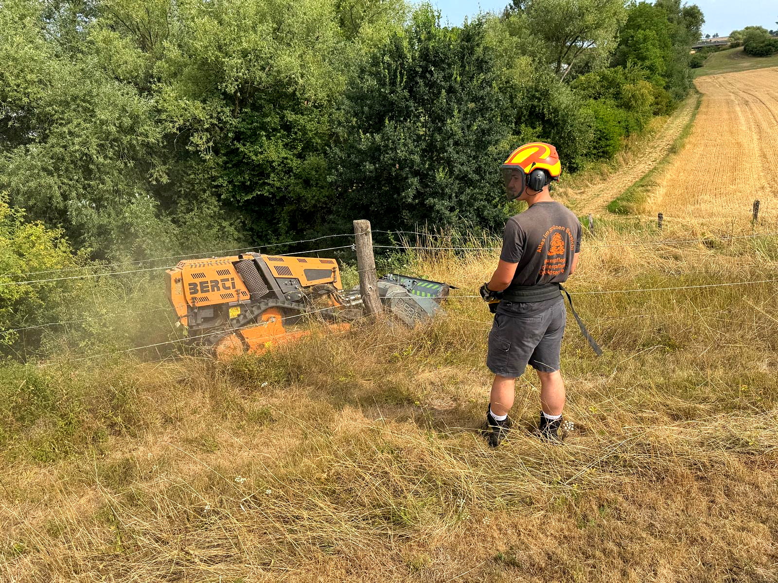 Mitarbeiter überwacht die funkgeführte BERTI-Mulchraupe bei der Böschungspflege. Mähraupe im Einsatz!